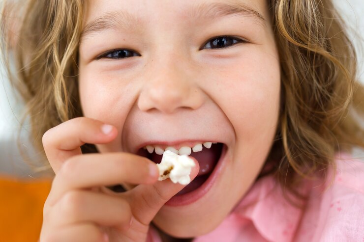 Niña pequeña sonríe y muestra sus pequeños dientes temporales